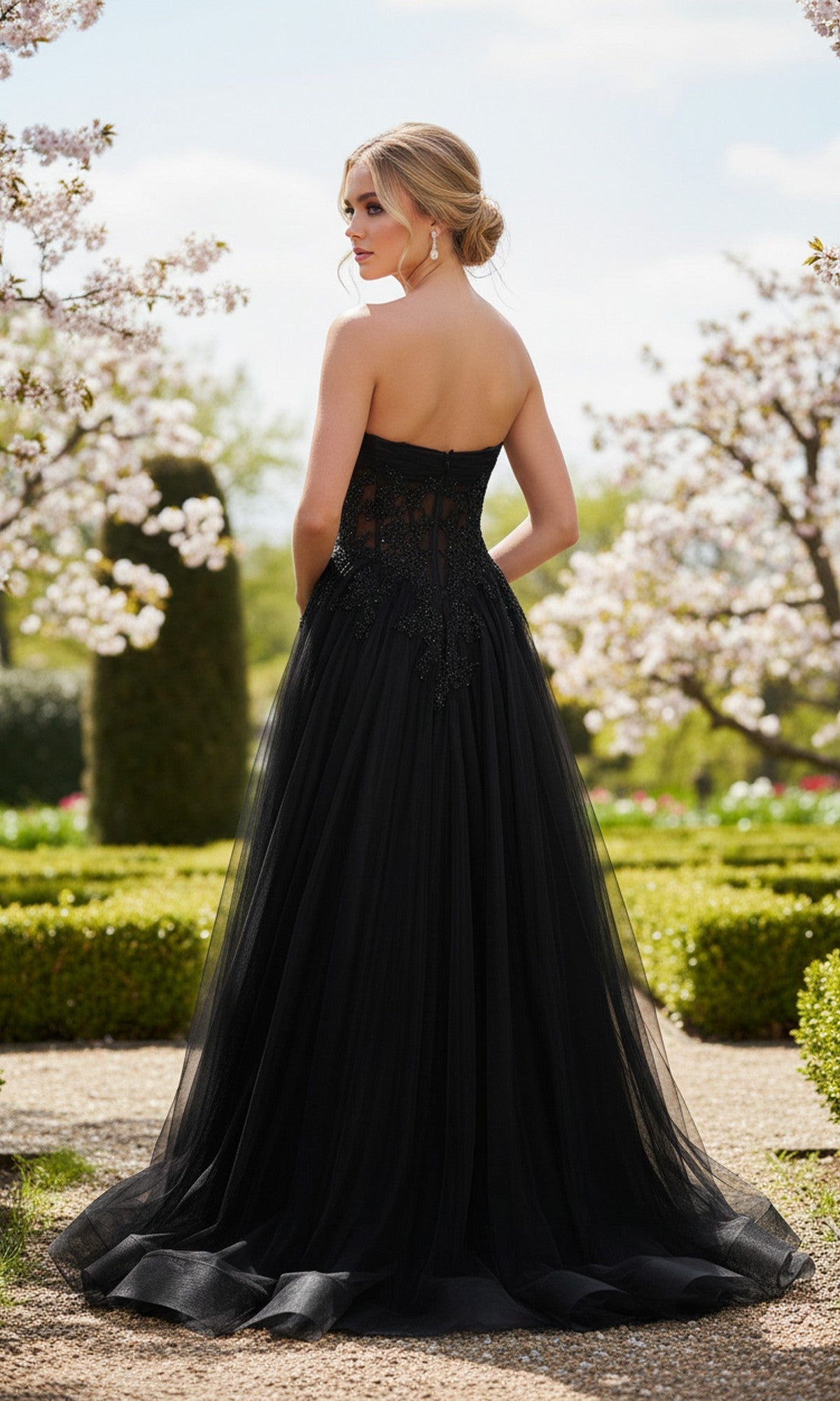 Wearing the La Femme 33528 long prom dress, a woman in a strapless gown with floral embroidery stands outdoors on a garden path, surrounded by blooming trees and greenery.